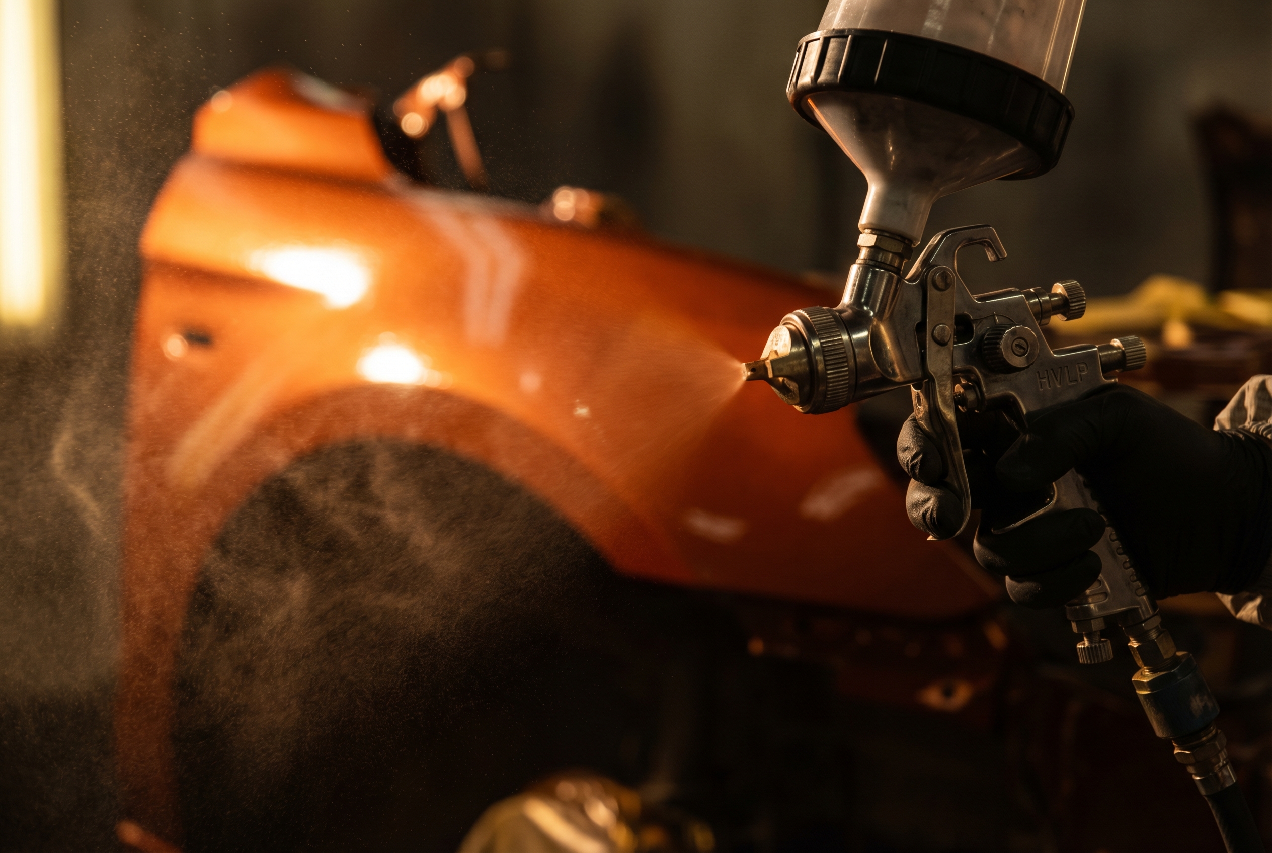 Professionelle HVLP Spritzpistole beim Auftragen von Metallic-Lack auf ein Fahrzeugteil